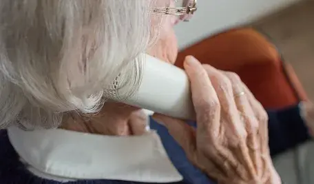 Starsza kobieta o siwych włosach, rozmawiająca przez telefon