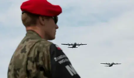 Funkcjonariusz Żandarmerii Wojskowej, w tle dwa lecące samoloty