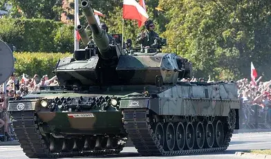 Czołg jadący w defiladzie i machający do zgromadzonych żołnierz