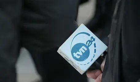 Pracownik TVN trzymający mikrofon z logo stacji