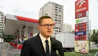 Minister energii Miłosz Motyka na tle stacji benzynowej.