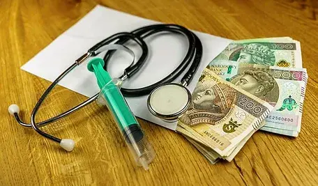 Koperta z pieniędzmi leżąca na stole razem ze strzykawką i stetoskopem