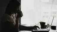 Kobieta z kubkiem pracująca przy laptopie