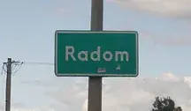 Zielona tablica drogowa z napisem ‘Radom’ przy drodze, w tle słup energetyczny i częściowo zachmurzone niebo