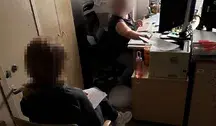 Zdjęcie przedstawia biuro, w którym przetwarzane są dokumenty. Dwie osoby siedzą przy biurku z komputerem i drukarką, jedna przekazuje dokumenty drugiej. Idealne do artykułów o śledztwach, zatrzymaniach, handlu zabytkami, sprawach kryminalnych w Polsce