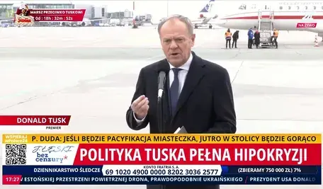 Donald Tusk, premier Polski, przemawia na konferencji prasowej na lotnisku. Na ekranie widać nagłówki krytykujące politykę Tuska, a także licznik odliczający czas do marszu opozycyjnego. Fotografia pokazuje polityczne napięcia, publiczne wystąpienia szefa rządu oraz reakcje opinii publicznej w kontekście polskiej polityki