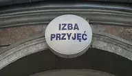 Wejście do izby przyjęć szpitala – znak z napisem ‘Izba Przyjęć’ nad wejściem, symbolizujący przeciążony system opieki zdrowotnej w Polsce i dramatyczny wzrost amputacji kończyn z powodu cukrzycy.