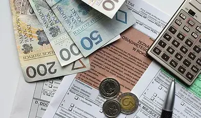 Pieniądze leżące na dokumentach, obok długopis i kalkulator