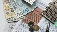 Pieniądze leżące na dokumentach, obok długopis i kalkulator