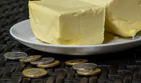 Kostka masła na talerzu i monety ułożone na stole
