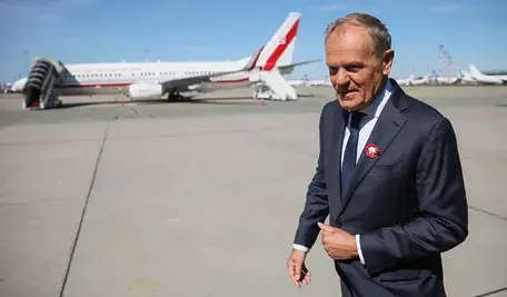 Premier Donald Tusk na tle samolotu