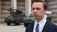 Wicemarszałek Sejmu Krzysztof Bosak podczas konferencji prasowej, w tle pojazdy wojskowe