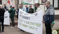 Grupa protestujących pracowników spółki FIBRIS trzymających transparenty z hasłami o dramatycznej sytuacji związanej z brakiem wypłat i blokadą kont przez ZUS. Na pierwszym planie widoczna jest biało-zielona flaga Polski oraz transparent z napisem: „PRZEZ WASZE DECYZJE MY GŁODUJEMY! ŻYJEMY W ZAWIESZENIU MIĘDZY PRACĄ A BRAKIEM ZAPŁATY!” Protest odbywa się przed siedzibą ZUS w Rzeszowie
