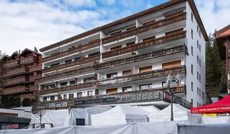 Budynek z barem Le Constellation w Crans-Montana, miejsce tragicznego pożaru sylwestrowego 2026, zabezpieczony biało-czerwonymi namiotami służb ratunkowych i policyjnymi barierkami