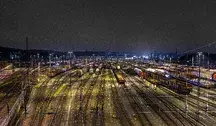 Nocny widok na rozległy dworzec kolejowy z setkami wagonów towarowych stojących na torach, symbolizujący transport kolejowy Ukrainy i rozwój przewozów cargo w Europie