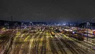 Nocny widok na rozległy dworzec kolejowy z setkami wagonów towarowych stojących na torach, symbolizujący transport kolejowy Ukrainy i rozwój przewozów cargo w Europie