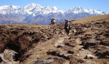 Dwóch turystów niosących plecaki w górach Himalajów, symbolizujący ryzyko i dramatyczne sytuacje podczas komercyjnych wypraw wysokogórskich na Mount Everest, gdy niekwalifikowane osoby pełnią rolę przewodników