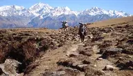 Dwóch turystów niosących plecaki w górach Himalajów, symbolizujący ryzyko i dramatyczne sytuacje podczas komercyjnych wypraw wysokogórskich na Mount Everest, gdy niekwalifikowane osoby pełnią rolę przewodników