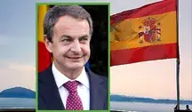 Były premier Hiszpanii José Luis Rodríguez Zapatero na tle hiszpańskiej flagi powiewającej nad wybrzeżem