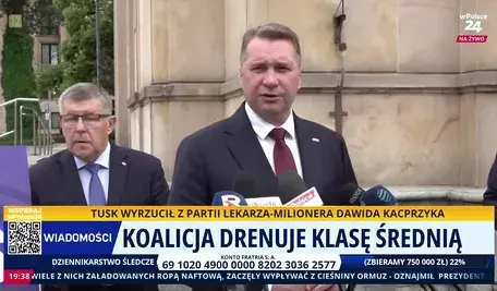 Przemysław Czarnek podczas konferencji prasowej przed budynkiem, udzielający wypowiedzi mediom, z widocznymi mikrofonami stacji telewizyjnych oraz paskiem informacyjnym na ekranie dotyczącym polityki gospodarczej i klasy średniej w Polsce.