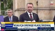 Przemysław Czarnek podczas konferencji prasowej przed budynkiem, udzielający wypowiedzi mediom, z widocznymi mikrofonami stacji telewizyjnych oraz paskiem informacyjnym na ekranie dotyczącym polityki gospodarczej i klasy średniej w Polsce.