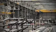 Wnętrze hali przemysłowej z konstrukcją stalową, liniami produkcyjnymi i elementami metalowych profili.