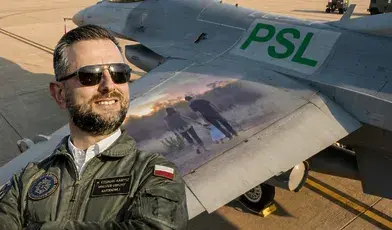 Władysław Kosiniak-Kamysz w ciemnych okularach na tle samolotu ze zdjęciem rodziny o logo PSL