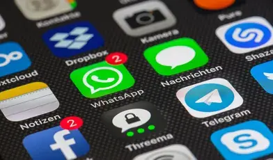 Zbliżenie na ekran smartfona z widocznymi ikonami aplikacji komunikacyjnych i społecznościowych, m.in. WhatsApp, Messenger, Telegram i Facebook, z oznaczeniami nieprzeczytanych powiadomień.