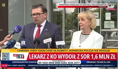 Konferencja prasowa polityków przed wejściem do szpitala w Warszawie. Mężczyzna w garniturze i czerwonym krawacie oraz kobieta w jasnej marynarce przemawiają do mediów, przed nimi ustawione są mikrofony telewizyjne. W tle widoczne wejście do budynku szpitala oraz oznaczenia transmisji na żywo.