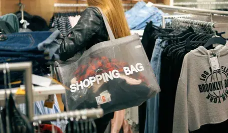 Kobieta z torbą na ramieniu podczas zakupów w sklepie odzieżowym