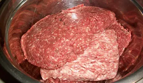 Surowe mięso mielone wołowe i wieprzowe w stalowej misce, widok z bliska na produkt mięsny używany w kuchni do przygotowania potraw takich jak kotlety czy sosy.
