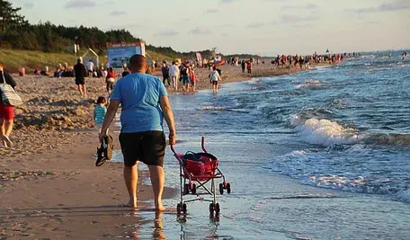 Mężczyzna z wózkiem spacerujący po plaży