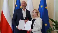 Minister sportu i wiceminister Żaneta Cwalina-Śliwiowska podczas oficjalnego wręczenia dokumentów powołania w resorcie sportu w Polsce, z flagami Polski i Unii Europejskiej w tle