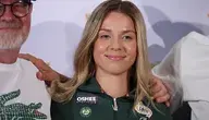 Maja Chwalińska podczas konferencji prasowej, ubrana w strój tenisowy z logo Roland Garros i sponsorów Oshee oraz Lotto, uśmiecha się do kamery