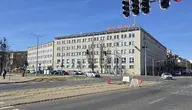 Budynek Urzędu Miejskiego w Gdańsku przy ruchliwej ulicy, widok z perspektywy skrzyżowania z sygnalizacją świetlną i tramwajowymi torami
