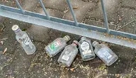 Małe butelki po alkoholu rozrzucone pod płotem