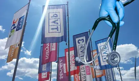 Flagi z logo TVP i dłoń trzymająca stetoskop