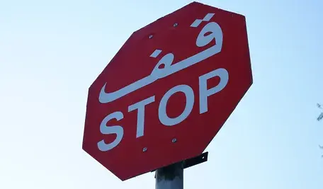 Znak STOP z dodatkowym napisem w języku arabskim, symbolizujący debatę o wprowadzaniu treści i symboli religijnych w przestrzeni publicznej oraz szkołach w USA.