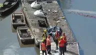 Pracownicy w kamizelkach ratunkowych stoją na odsłoniętym dnie zbiornika wodnego przy zaporze, gdzie poziom wody został znacznie obniżony w trakcie opróżniania Jeziora Pilchowickiego.
