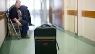 Walizka stojąca na korytarzu szpitalnym, w tle siedzi pacjentka