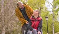 Wsparcie dla osób z niepełnosprawnością – opiekun pomaga mężczyźnie na wózku inwalidzkim