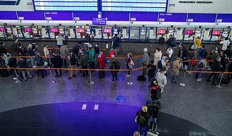 Pasażerowie czekający w kolejce do kasy biletowej PKP