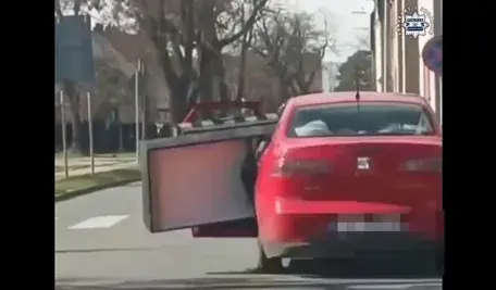 Seat z otwartym bagażnikiem, z którego wystaje duża kanapa przewożona w niebezpieczny sposób ulicami Kędzierzyna-Koźla. Nietypowy transport zakończył się mandatem.