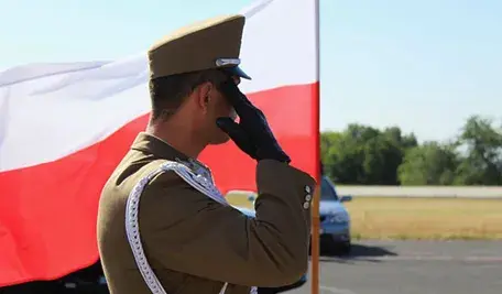 Żołnierz na tle biało-czerwonej flagi