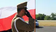Żołnierz na tle biało-czerwonej flagi