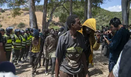 Migranci z Afryki Subsaharyjskiej eskortowani przez służby bezpieczeństwa w pobliżu granicy Maroka z hiszpańską enklawą Ceuta