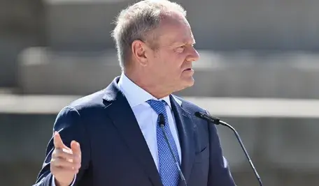 Premier Donald Tusk podczas publicznego wystąpienia przy mikrofonach. Fotografia ilustruje artykuł dotyczący jego emerytur, wynagrodzenia premiera oraz pozostałych dochodów wykazanych w oświadczeniu majątkowym