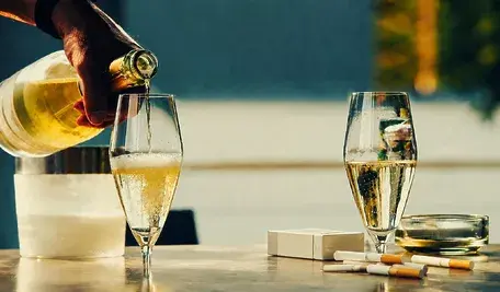Kieliszki z alkoholem oraz papierosy na stole – grafika ilustracyjna do artykułu o nowym podatku od używek