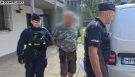 Policjanci prowadzą zatrzymanego mężczyznę podejrzanego o podszywanie się pod masażystę w sanatorium w Cieplicach