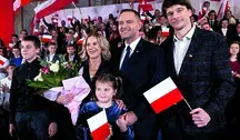 Karol Nawrocki z rodziną podczas uroczystości z polskimi flagami w tle.